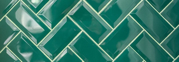 Glänzende grüne Fliesen in Fischgrätmuster.